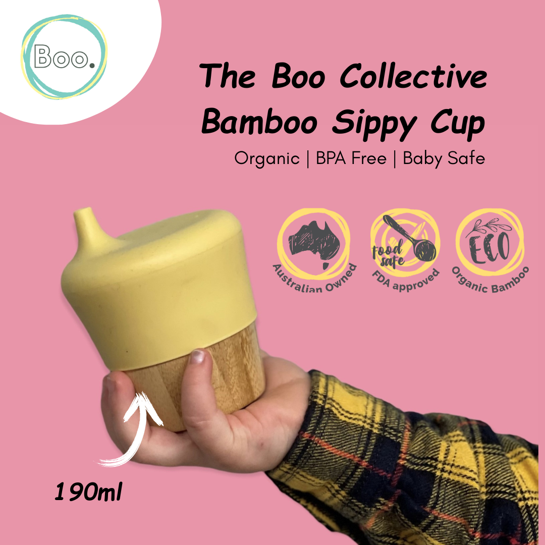 Bamboo sippy cup held by a hand with 'Boo' brand logo on pink background