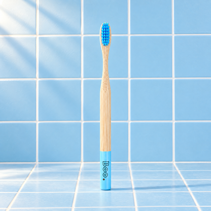 Boo adult bamboo toothbrush with blue bristles and a blue end cap, standing on blue tiles